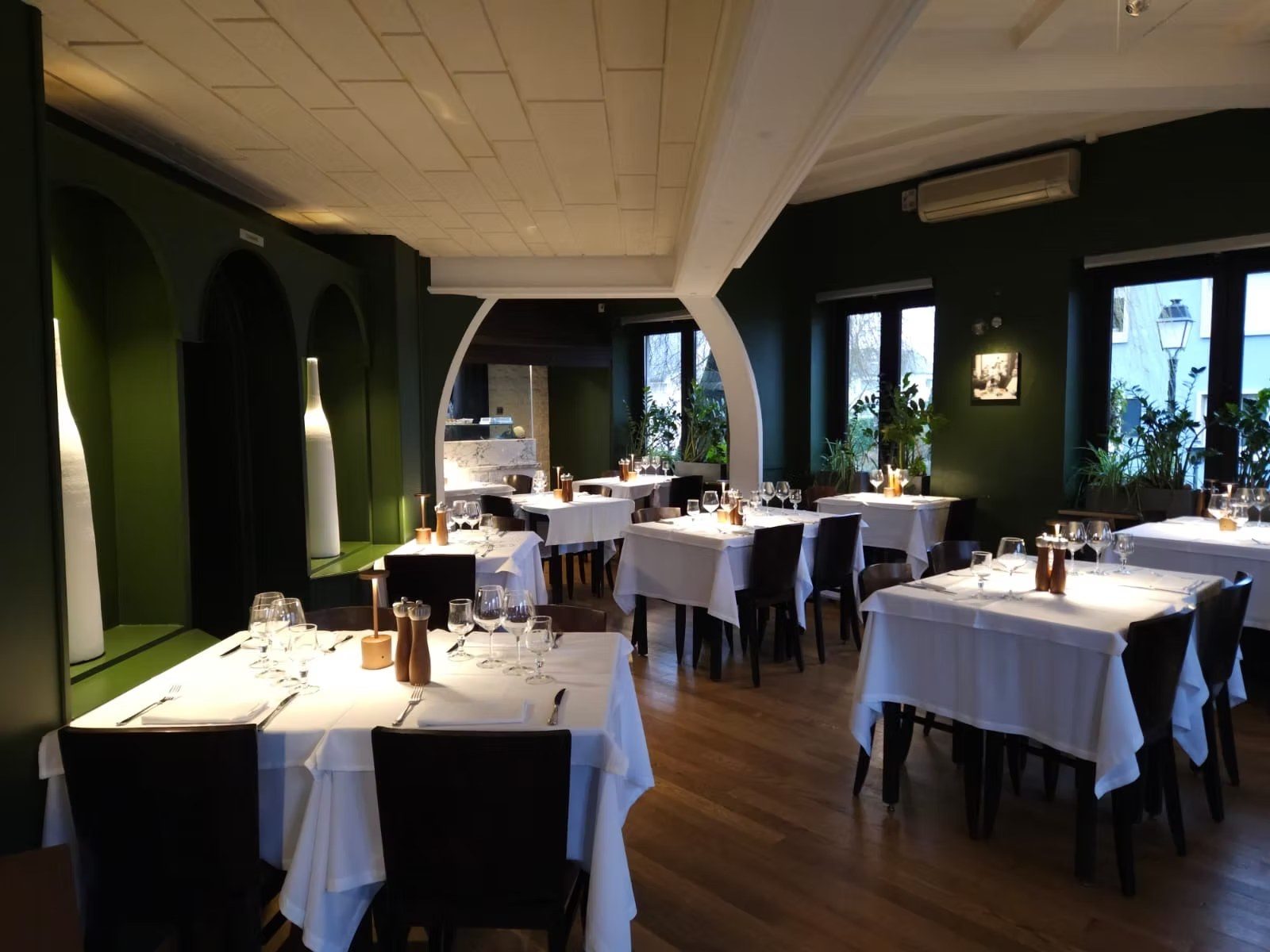 Salle à manger de La Rusticana, murs vert sapin, nappes blanches, arches voûtées